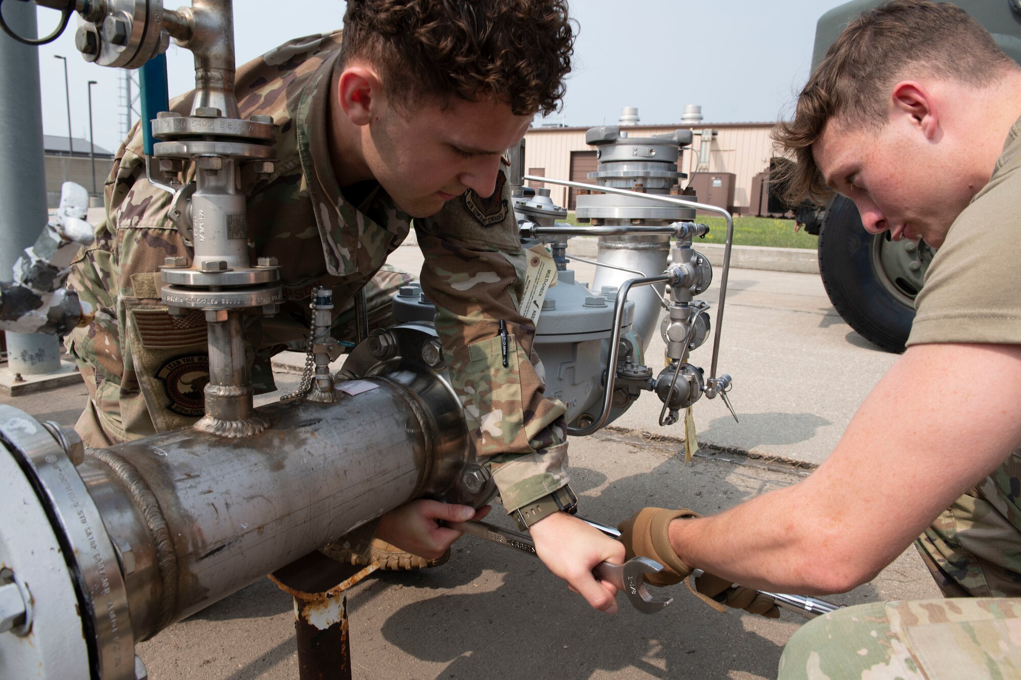 2 service members work on a hydrant fuel pipe.