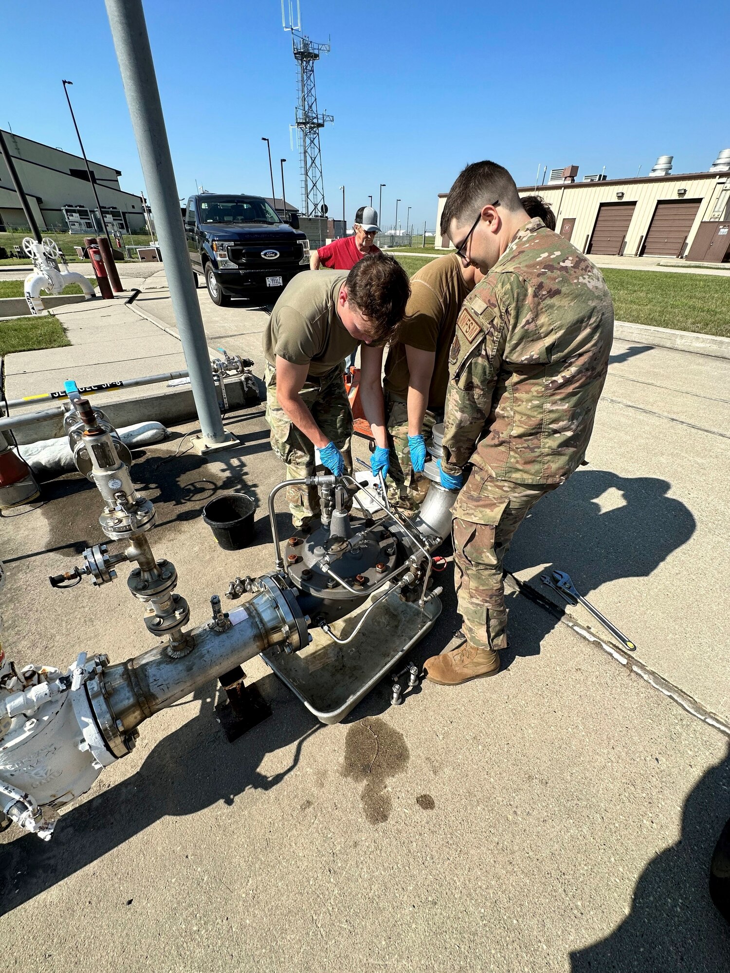 3 service members work on a hydrant fuel pipe.