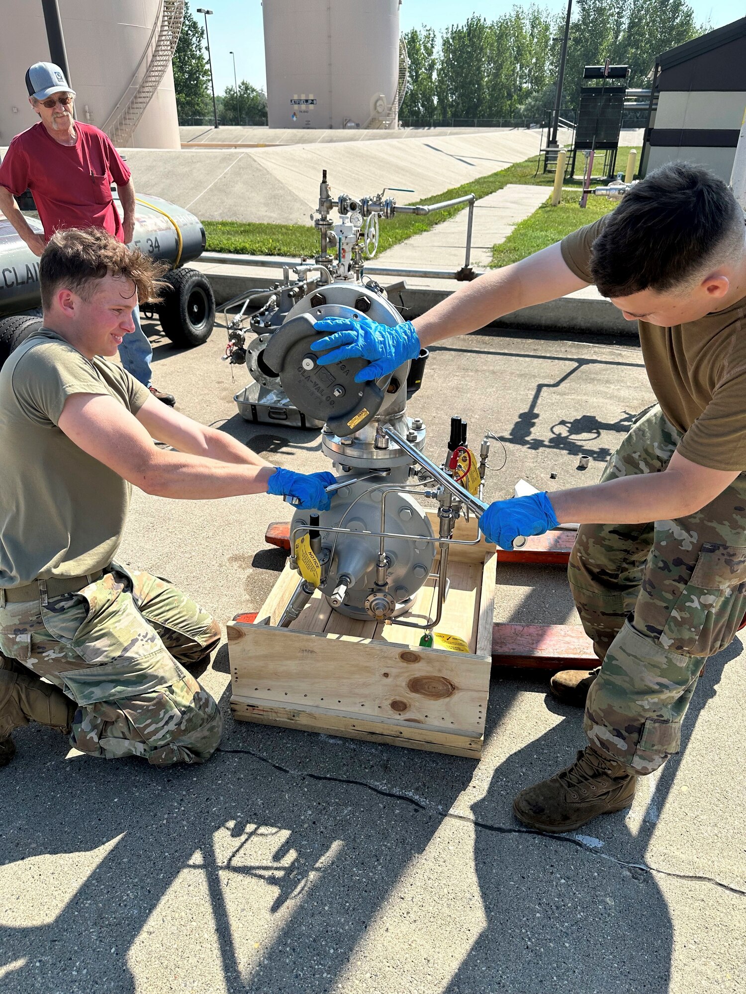2 service members work on a hydrant valve.