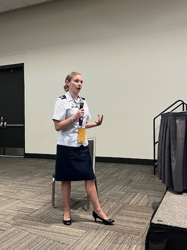 photo of uniformed U.S, Space Force Guardian standing holding a microphone in a conference room