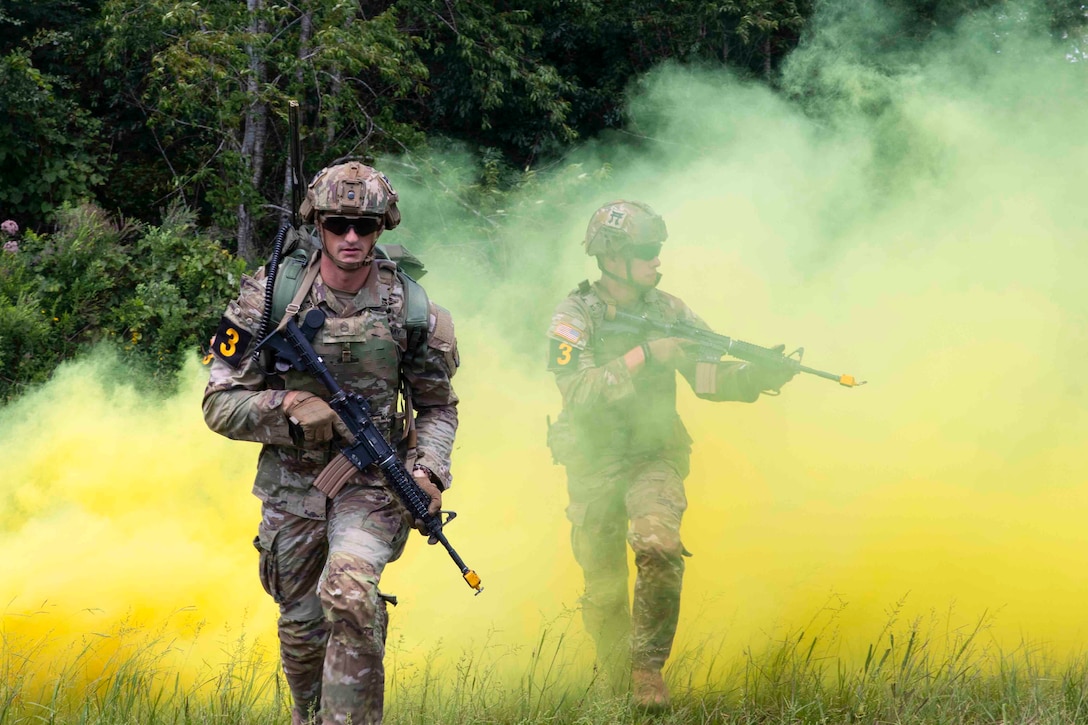 Two soldiers move through a haze of yellow smoke.