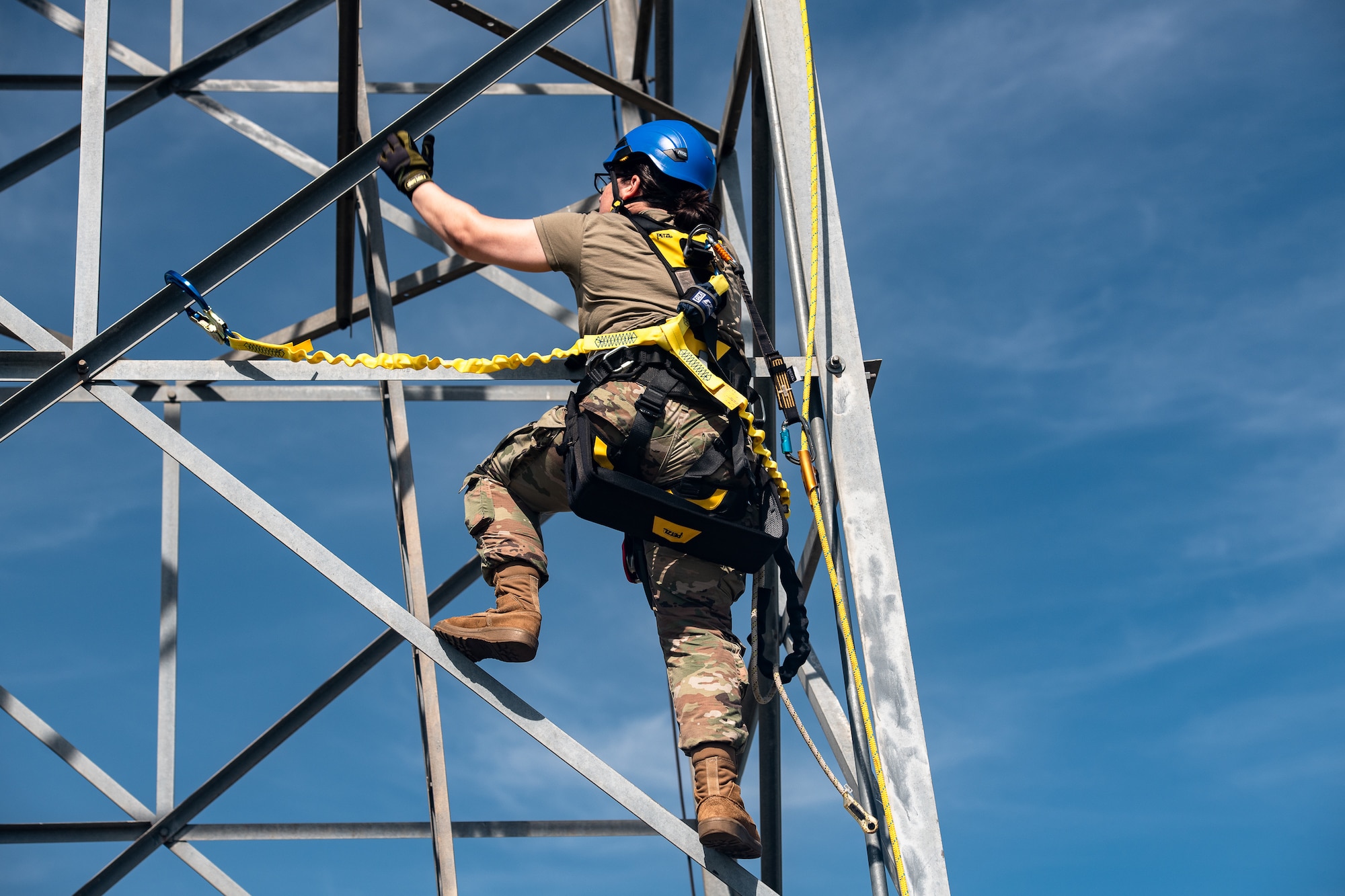 an Airman climbs an antenna tower during rappelling training