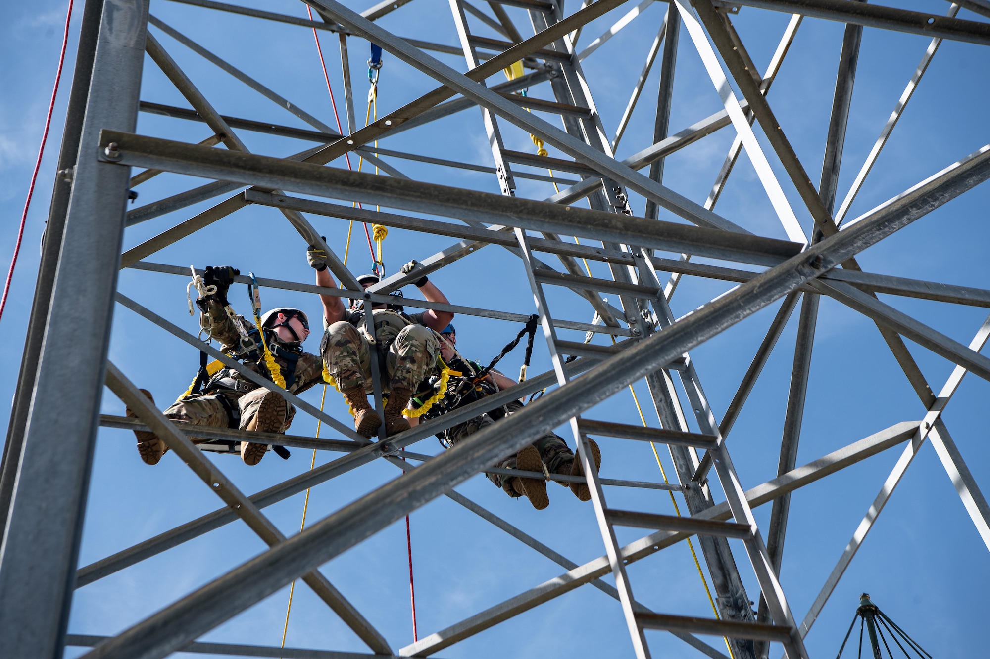 Airmen cling to the side of an antenna tower during a rescue training scenario