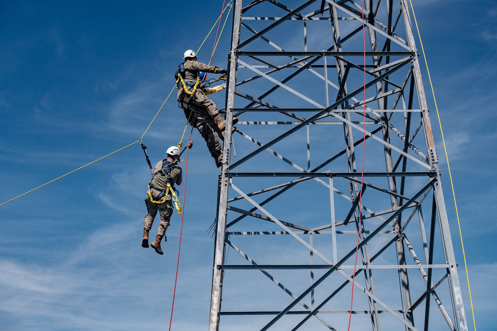 An Airman is lowered from a metal antenna tower during a rescue training scenario