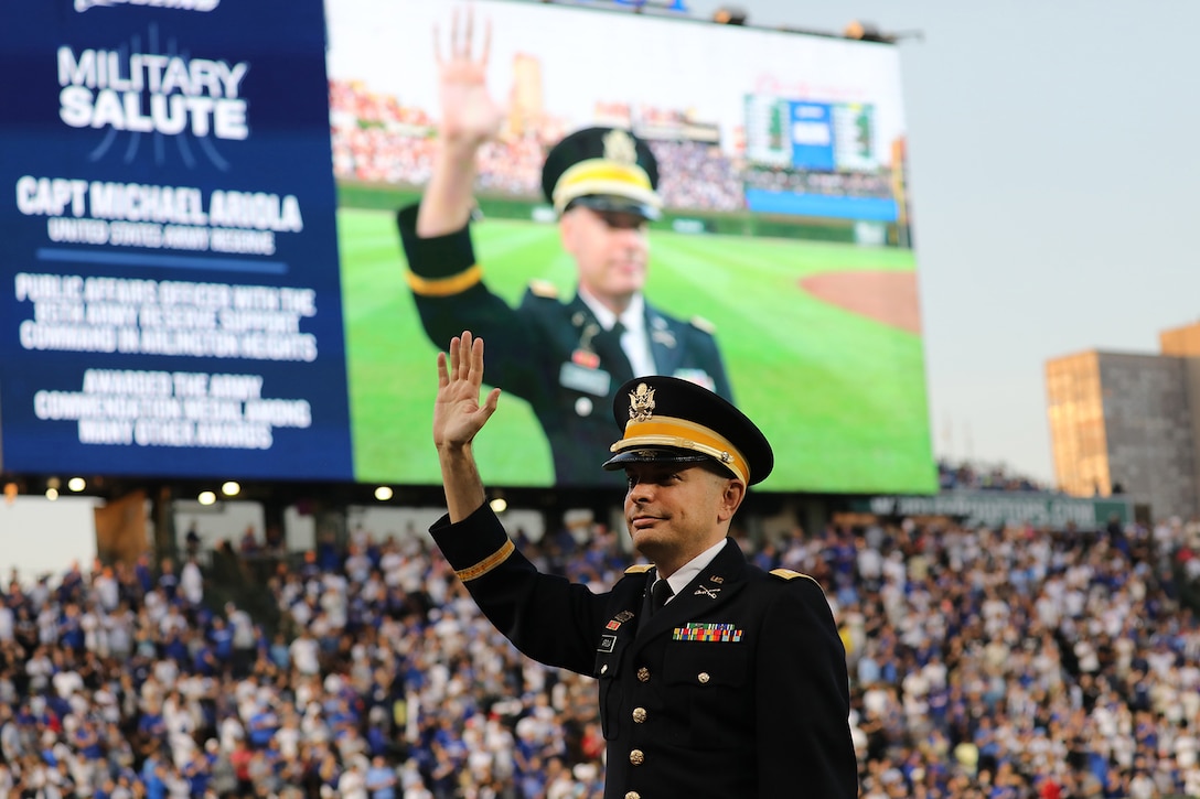 Capt. Michael Ariola, Public Affairs Officer, 85th U.S. Army Reserve Support Command, waves to cheering baseball fans during the Military Salute at the Crosstown Series featuring the Chicago Cubs and Chicago White Sox on August 16, 2023, at Wrigley Field.