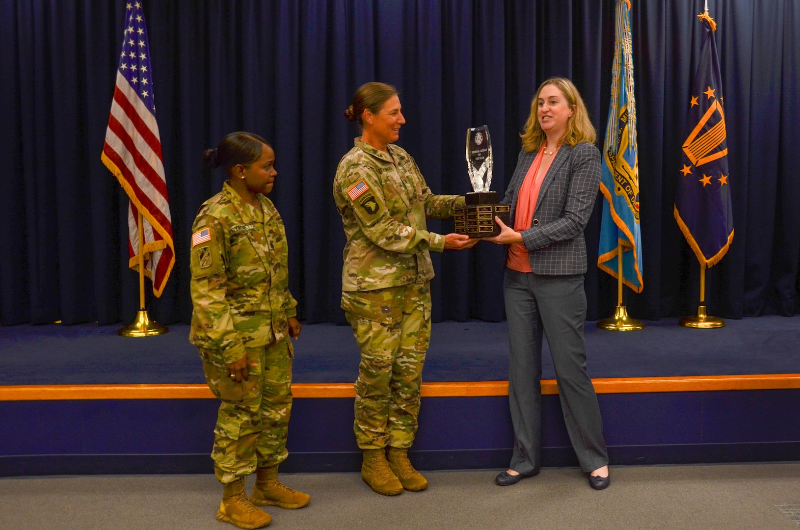 Dr. Katie Helland, director of Military Accession Policy, presents Chicago Federal Executive Board's Agency of the Year trophy to Col. Megan Stallings, USMEPCOM commander, and Command Sgt. Maj. Yveline Symonette, USMEPCOM senior enlisted advisor.