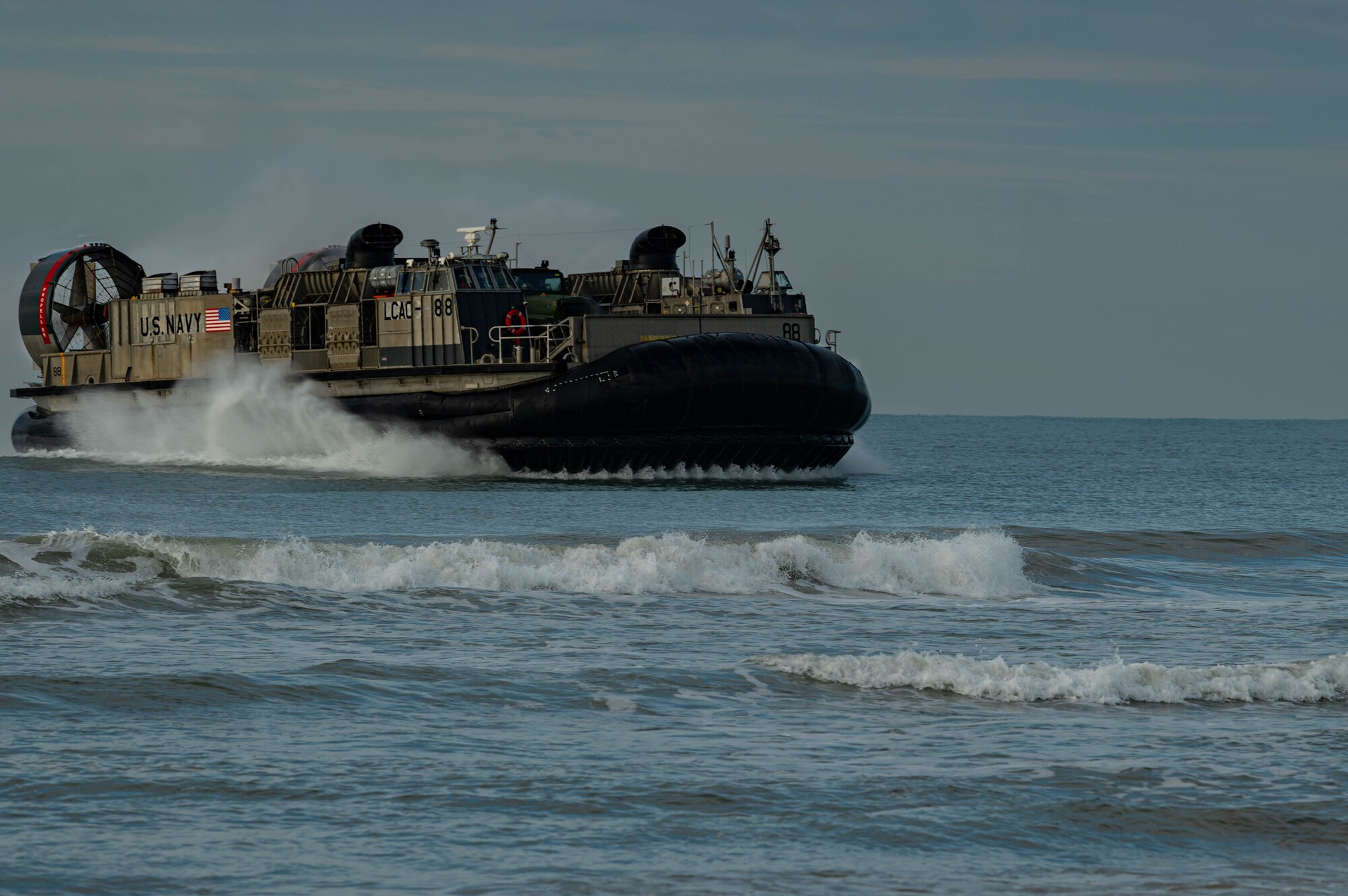 Navy Expeditionary Combat Command Seabees assigned to Naval Mobile Construction Battalion 11 are delivered to shore by U.S. Navy Landing Craft, Air Cushion (LCAC) 88 at Onslow Beach, Marine Corps Base Camp Lejeune, North Carolina, August 9, 2023, during Large-Scale Exercise 2023 (LSE 2023). LSE 2023 demonstrates the Navy’s and Marine Corps’ ability to employ precise, lethal, and overwhelming force globally across six maritime component commands, seven numbered fleets, and 22 time zones. LSE 2023 merges real-world operations with virtually constructed scenarios to create a realistic training environment that allows Sailors and Marines to train how they will fight, regardless of geographic boundaries. (U.S. Air Force photo by Airman 1st Class Rebecca Sirimarco-Lang)