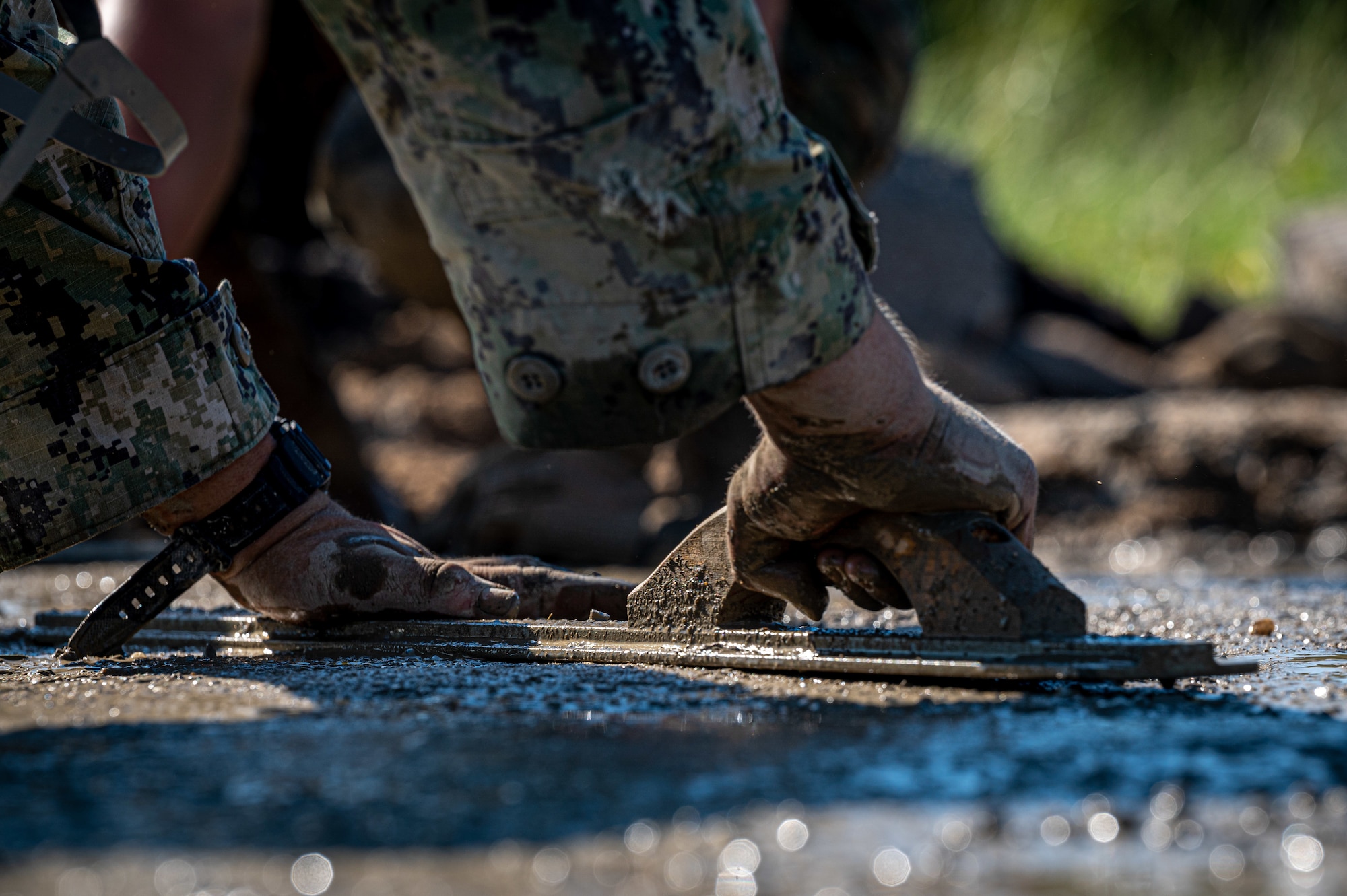 Navy Expeditionary Combat Command Seabees assigned to Naval Mobile Construction Battalion 11 level out wet concrete to fill a crater on an airfield ramp during airfield damage repair efforts as part of Large Scale Exercise (LSE) 2023 at Seymour Johnson Air Force Base, North Carolina, July 10, 2023. LSE 2023 demonstrates the Navy’s and Marine Corps’ ability to employ precise, lethal, and overwhelming force globally across six maritime component commands, seven numbered fleets, and 22 time zones. LSE 2023 merges real-world operations with virtually constructed scenarios to create a realistic training environment that allows Sailors and Marines to train how they will fight, regardless of geographic boundaries. (U.S. Air Force photo by Airman 1st Class Leighton Lucero)
