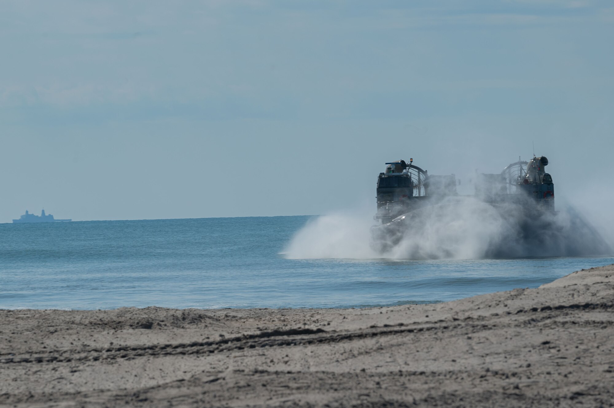 Navy Expeditionary Combat Command Seabees assigned to Naval Mobile Construction Battalion 11 and their construction vehicles are delivered to shore by U.S. Navy Landing Craft Air, Cushion (LCAC) 88 at Onslow Beach, Marine Corps Base Camp Lejeune, North Carolina, August 9, 2023,  during Large-Scale Exercise 2023 (LSE 2023). LSE 2023 demonstrates the Navy’s and Marine Corps’ ability to employ precise, lethal, and overwhelming force globally across six maritime component commands, seven numbered fleets, and 22 time zones. LSE 2023 merges real-world operations with virtually constructed scenarios to create a realistic training environment that allows Sailors and Marines to train how they will fight, regardless of geographic boundaries. (U.S. Air Force photo by Airman 1st Class Rebecca Sirimarco-Lang)