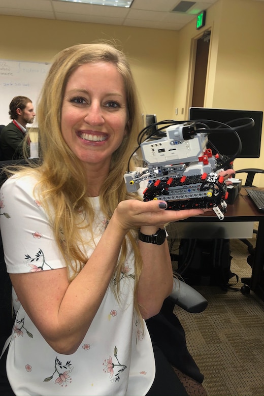 A person smiles while holding a handheld robot.