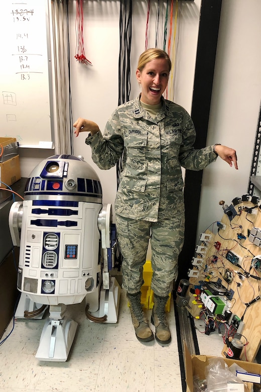 A uniformed service member stands next to a replica of a robot.
