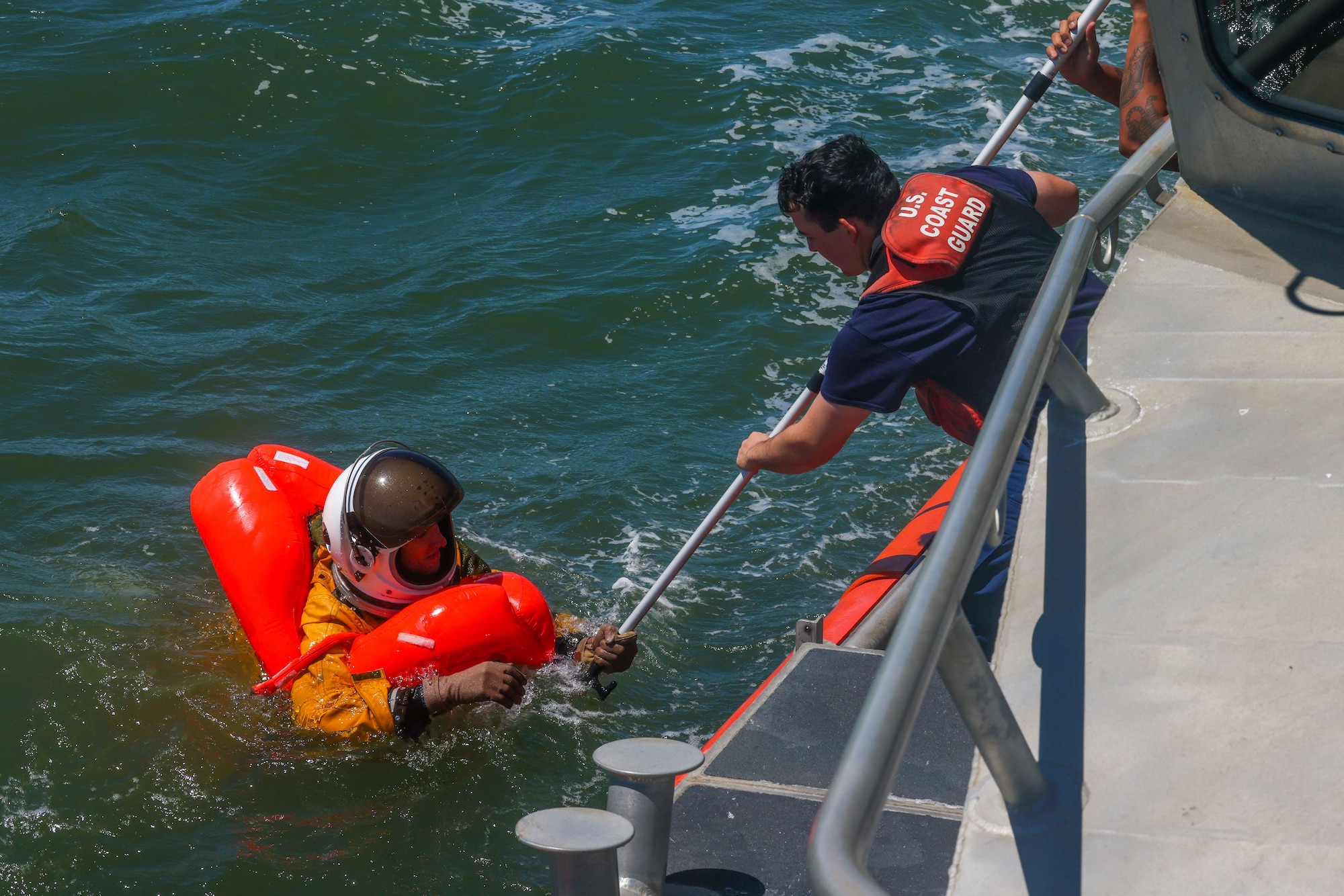 U.S. Air Force Capt. Kyle Carver, U-2 Pilot, 99 Reconnaissance Squadron, grabs hold of the rescue pole extended by U.S. Coast Guard Seaman Ethan Carter, Fireman, U.S. Coast Guard San Francisco Sector in the San Francisco Bay, California on Aug. 17, 2023.