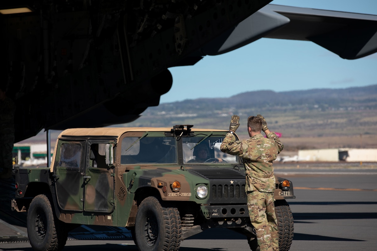 A service member motions to the driver of military vehicle.