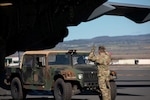 A service member motions to the driver of military vehicle.