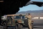 A group of service members carry packs as they walk away from two helicopters.