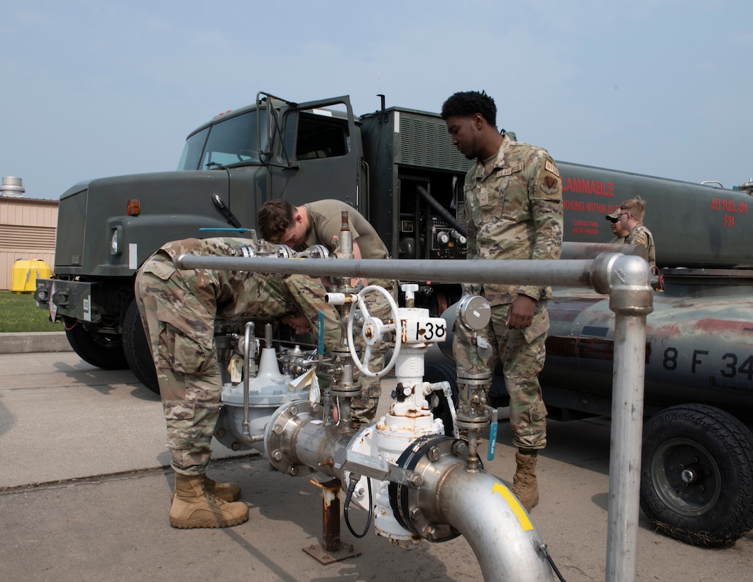 3 service members work on a hydrant fuel pipe.