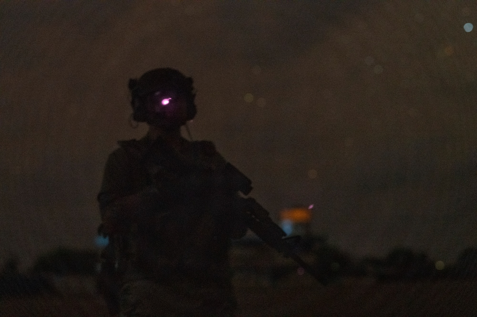 Photo of a man holding a rifle at night