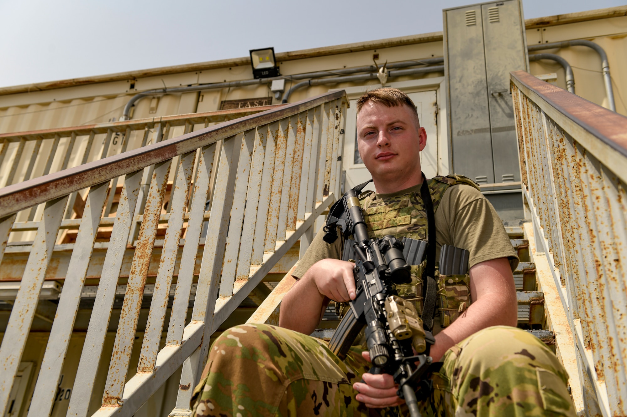 Photo of a man sitting on stairs with a rifle