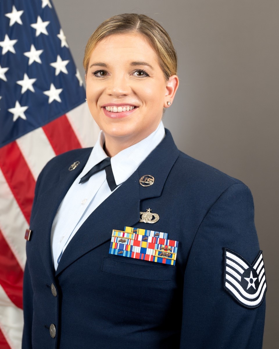 Technical Sergeant Melissa Lackore in service dress with American flag in the background