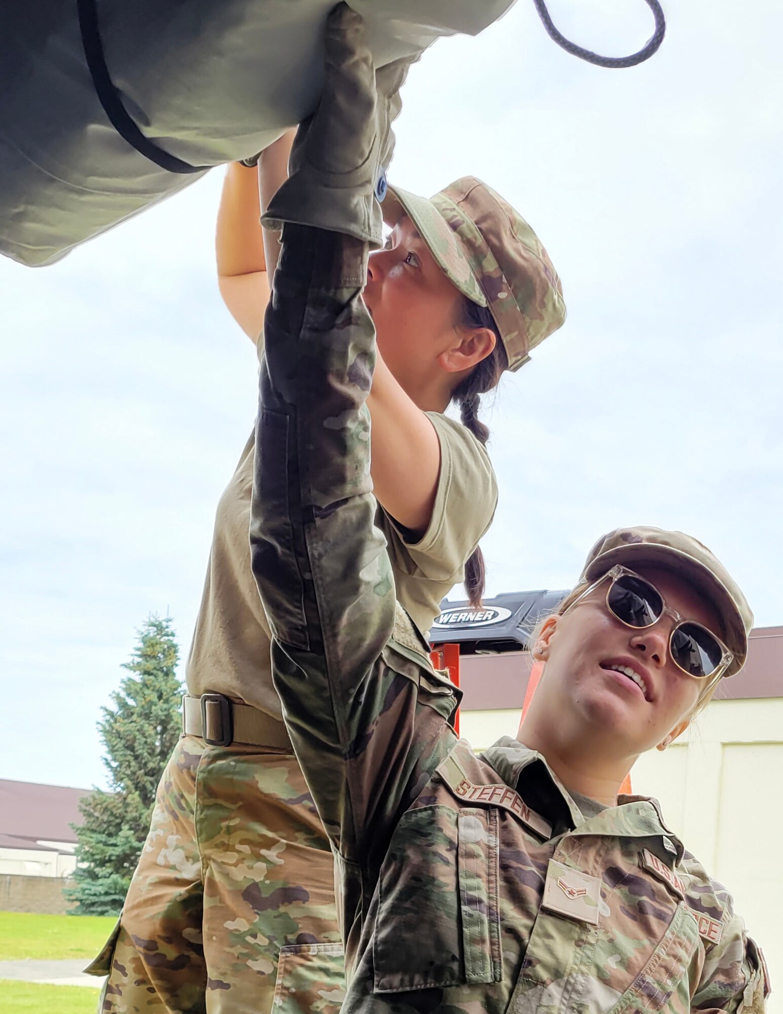 U.S. Air Force Airman 1st Class Sari Steffen, holds up a part of the Alaska Small Shelter System while Tech. Sgt. TSgt Dieuhuyen Johnson, left, secures it in place at Joint Base Elmendorf-Richardson, Alaska, July 26, 2023.