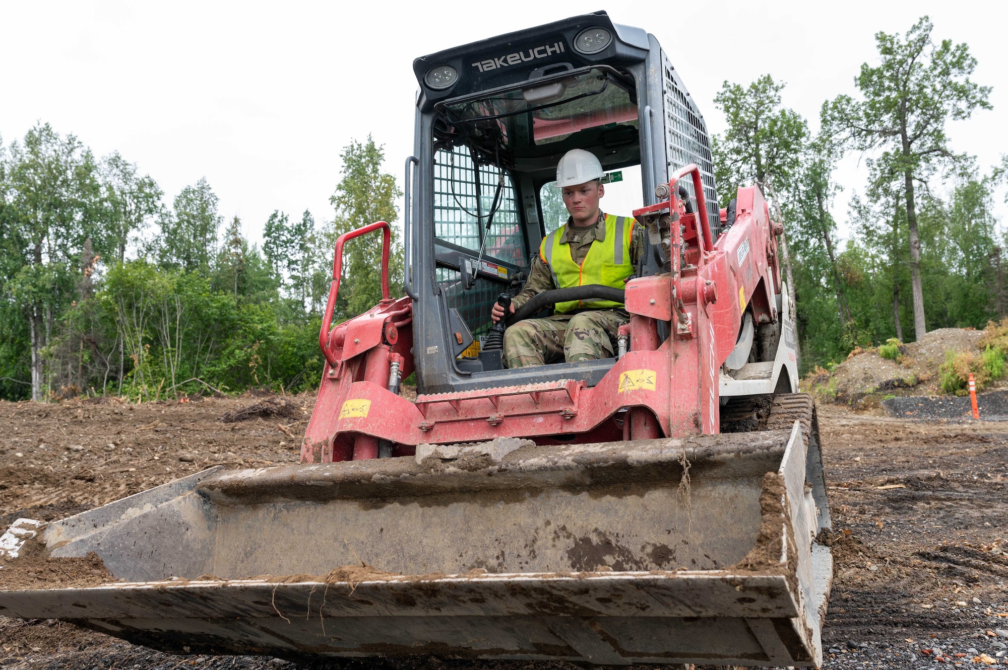 Senior Airman Nathan Smith, 934th Civil Engineer Squadron civil engineering apprentice, operates the skid loader to backfill holes with dirt or cement at Joint Base Elmendorf-Richardson, Alaska, Aug. 9, 2023. (U.S. Air Force photo by Senior Airman Colten Tessness)