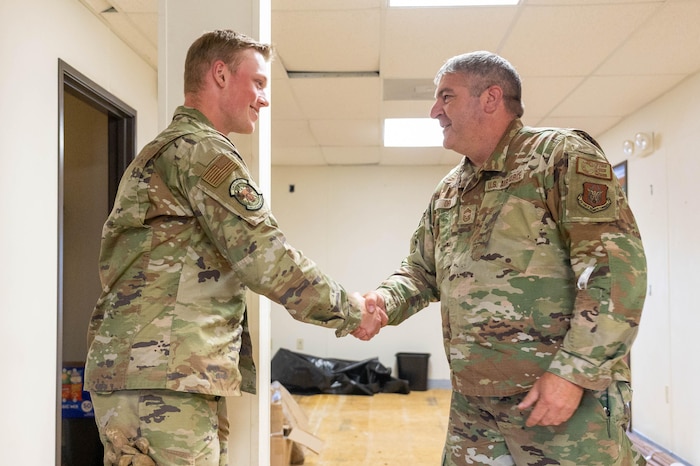 Chief Master Sgt. James Orr, 934th Civil Engineer Squadron chief of civil engineering operations, right, presents a challenge coin to Senior Airman Nathan Smith, 934 CES engineering apprentice, left, at Joint Base Elmendorf-Richardson, Alaska, Aug. 10, 2023. The commander and senior leadership recognized him for his innovation and positive attitude. (U.S. Air Force photo by Senior Airman Colten Tessness)