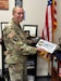 The commandant for the 83rd United States Army Reserve Readiness Training Academy, Lt. Col. Mary Drilling shows off her Kentucky state trooper baseball cap and license plate Aug. 22, 2023. Lt. Col. Drilling spent four years as a Kentucky police officer prior to her selection to the Active Guard Reserve.