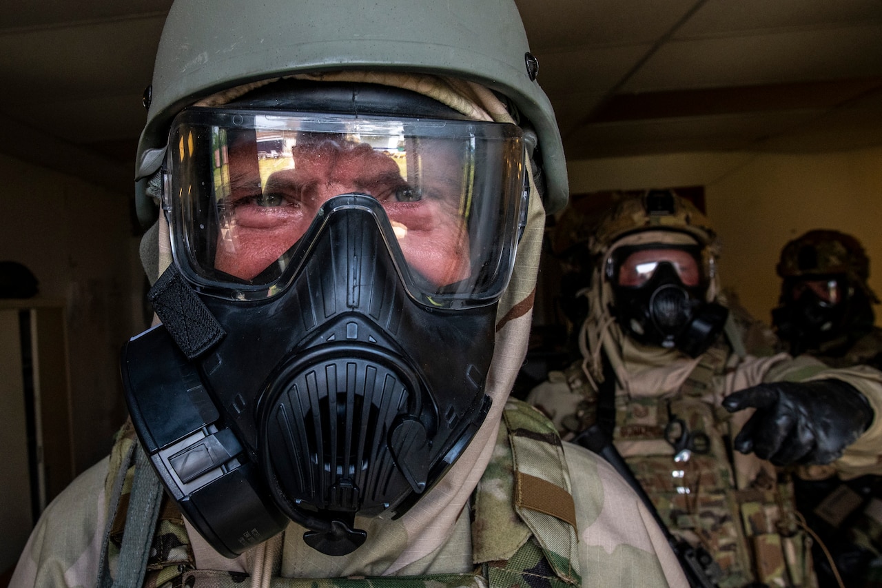 Service members wear gas masks during an exercise.