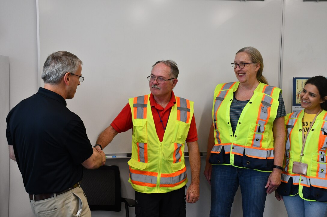 Director hands out coins to employees in safety gear