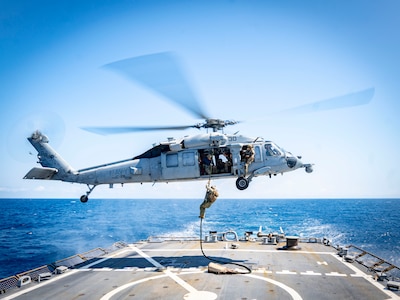 Navy Expeditionary Combat Command Sailors assigned to Mobile Diving and Salvage Unit (MDSU) 2 fast-rope onto the Arleigh Burke-class guided-missile destroyer USS Porter (DDG 78) for a simulated expeditionary battle damage assessment and repair during a general quarters drill, August 12, 2023. Porter is participating in U.S. Fleet Forces Command's Large Scale Exercise 2023, which provides a venue to test and refine current and new technologies and platforms to reinforce our current position as a supreme maritime force and provide feedback used to inform future innovation. (U.S. Navy photo by Interior Communications Electrician 3rd Class Hailey A. Servedio)