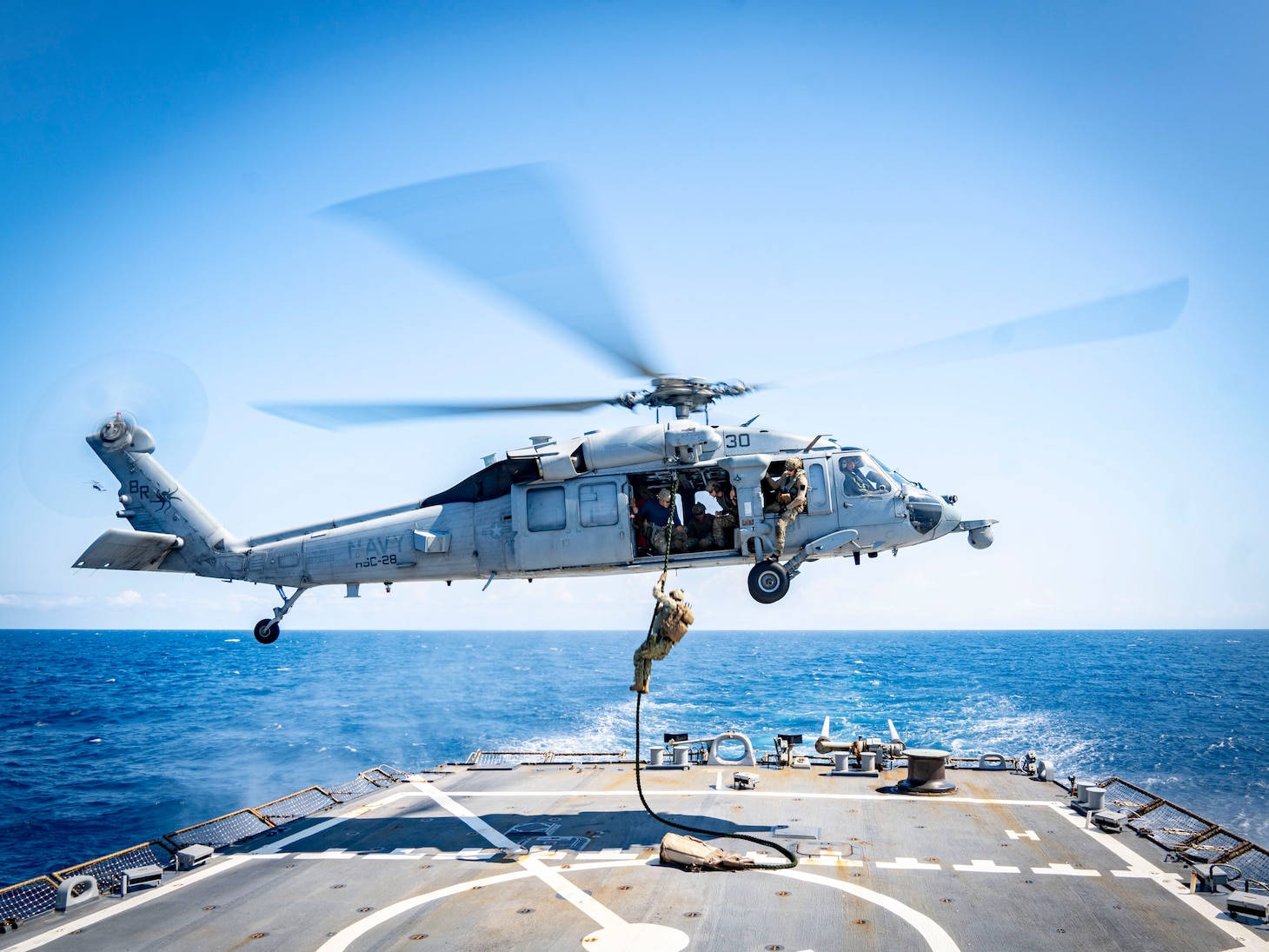 Navy Expeditionary Combat Command Sailors assigned to Mobile Diving and Salvage Unit (MDSU) 2 fast-rope onto the Arleigh Burke-class guided-missile destroyer USS Porter (DDG 78) for a simulated expeditionary battle damage assessment and repair during a general quarters drill, August 12, 2023. Porter is participating in U.S. Fleet Forces Command's Large Scale Exercise 2023, which provides a venue to test and refine current and new technologies and platforms to reinforce our current position as a supreme maritime force and provide feedback used to inform future innovation. (U.S. Navy photo by Interior Communications Electrician 3rd Class Hailey A. Servedio)