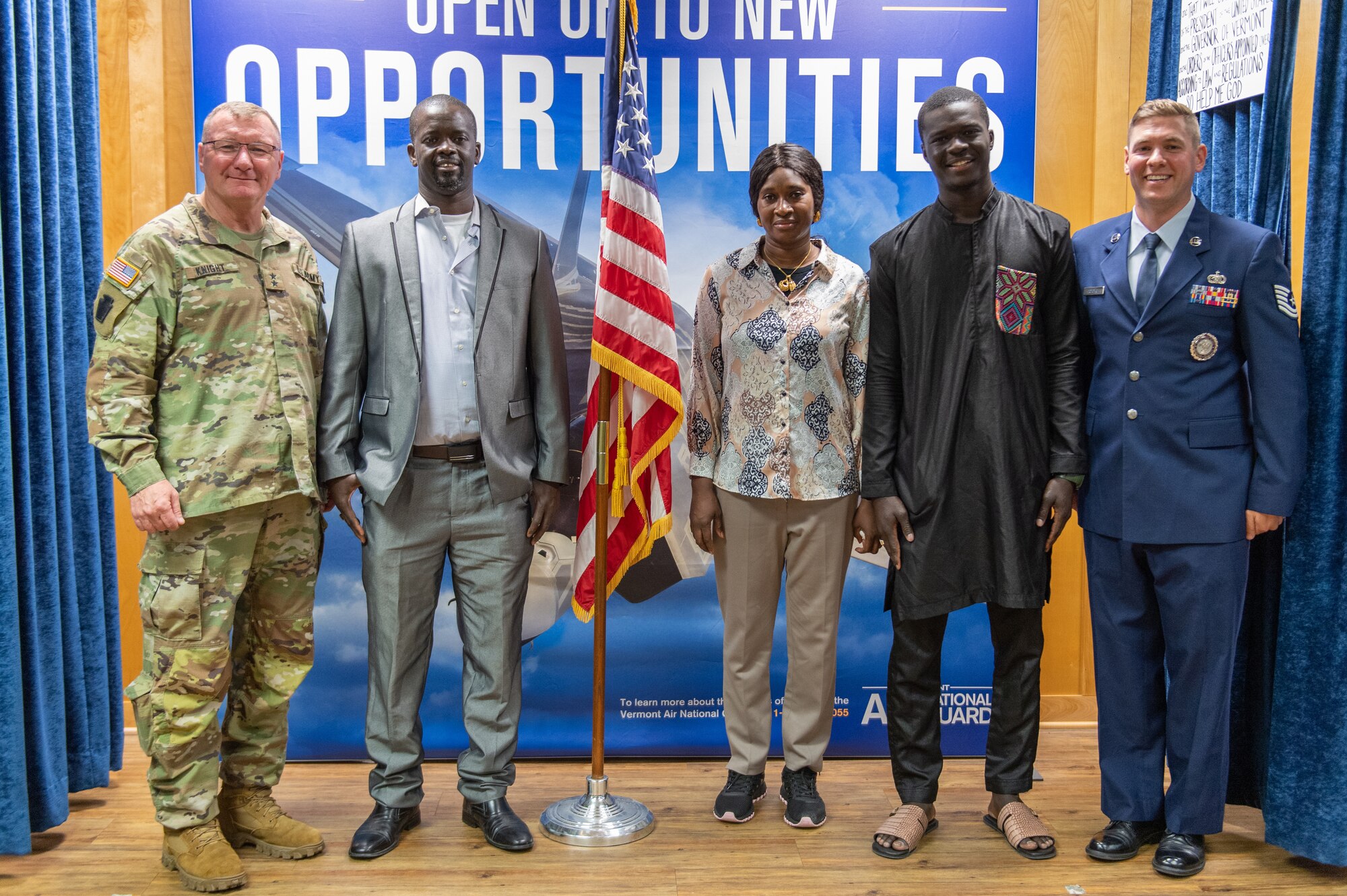 Photo of U.S. Army Maj. Gen. Gregory Knight (left), the Adjutant General of the Vermont National Guard and Tech. Sgt. Paul Popovich (right), a recruiter at the 158th Fighter Wing, standing for a photo with the Vermont Air National Guard’s newest Airman, Libass Mbengue’s along with his parents at the Vermont Air National Guard Base, South Burlington, Vermont May 18, 2023.