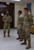 U.S. Army Sgt. Maj Eric Bonner (left), a Transportation Senior Sergeant with the 842nd Transportation Battalion, 597th Transportation Brigade, Surface Deployment and Distribution Command, presents challenge coins to Spc. Bryan Nunez (middle) and Spc. Aaron Rose (right), transportation management coordinators assigned to the 541st Division Sustainment Support Battalion,1st Infantry Division Sustainment Brigade, 1st Inf. Div., at 541st DSSB headquarters on Fort Riley, Kansas, August 10, 2023. Nunez and Rose were selected by their noncommissioned officer to be coined by Bonner for their hard work and commitment to service. (U.S. Army photo by Pfc. Autumn Johnson