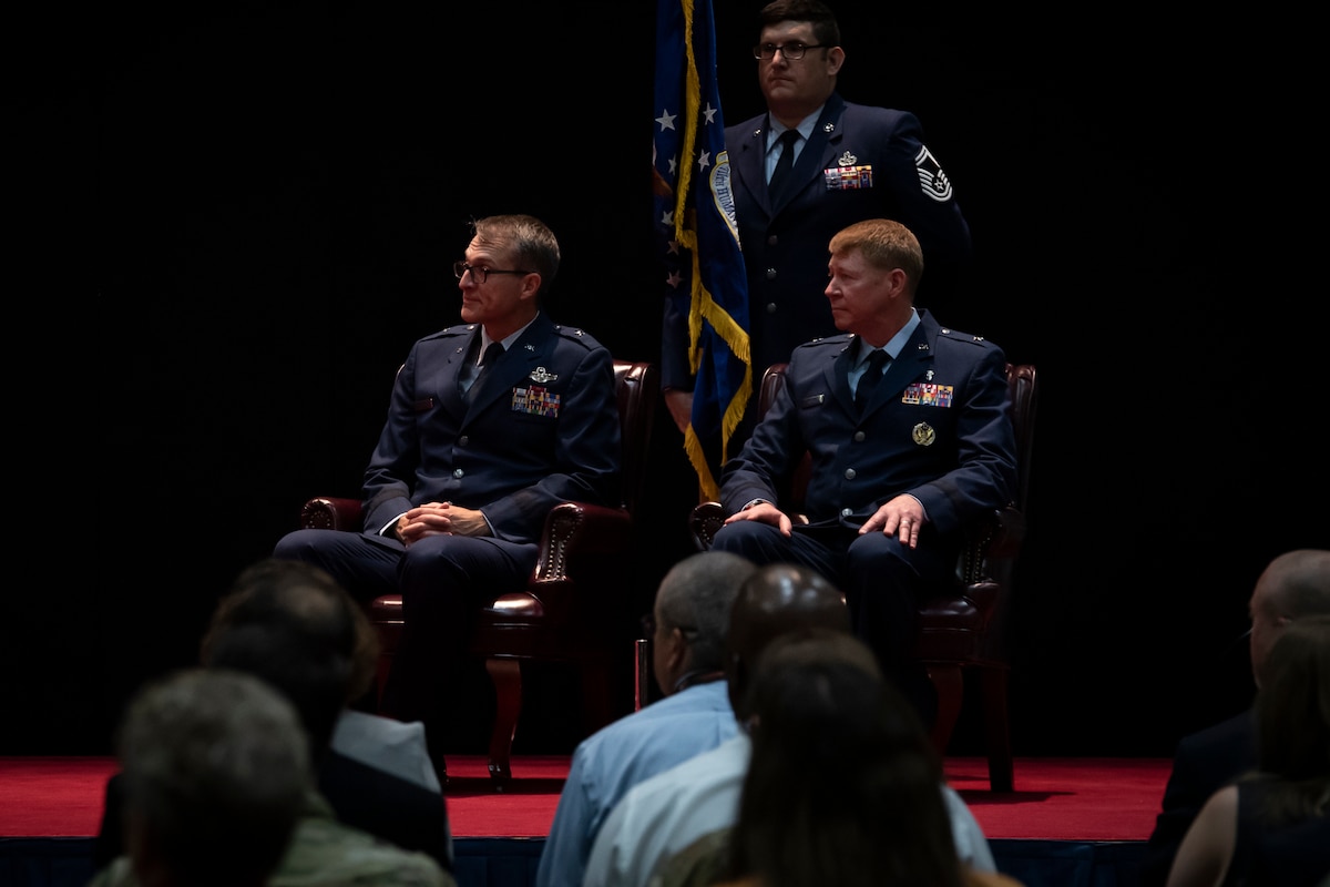 Brig. Gen. Scott A. Cain, left, commander, Air Force Research Laboratory, or AFRL, and Brig. Gen. (Dr.) Robert K. Bogart, right, listen to the narrator’s remarks during an assumption of command ceremony for AFRL’s 711th Human Performance Wing while Senior Master Sgt. Michael Booth, superintendent, AFRL Human Effectiveness Directorate, looks on at the National Museum of the U.S. Air Force, Aug. 21, 2023. (U.S. Air Force photo / Richard Eldridge)