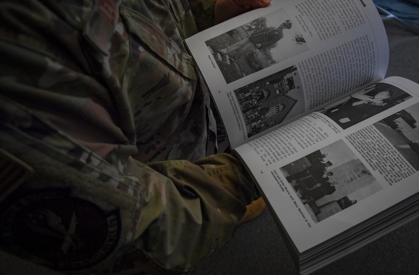 Military member opens a book and reads a page.