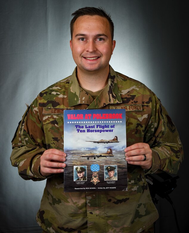 A military member holds a book close to him for a photo.