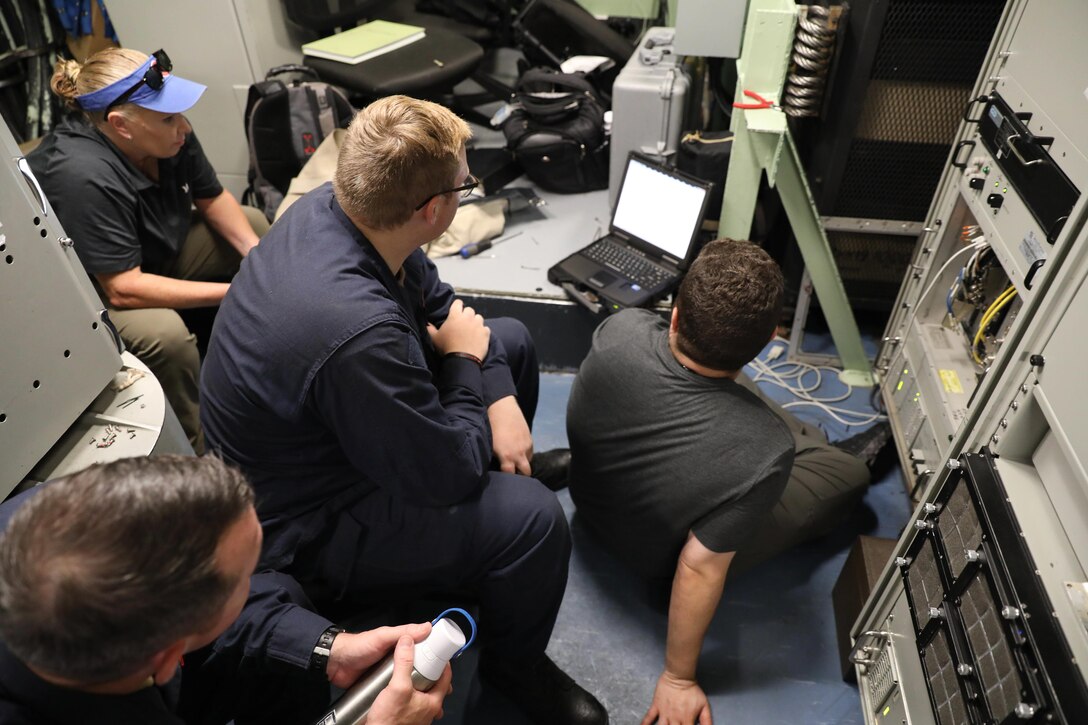LIMASSOL, Cyprus (Aug. 16, 2023) Technical representative Samuel A Montalvo, right, and technical representative Beverly Morris, left, both from Naval Information Warfare Center Atlantic, help Electronic Technician 3rd Class Ron Dobbs, middle, and Electronic Technician 1st Class Christopher Caviness, bottom, both assigned to Arleigh Burke-class guided-missile destroyer USS Ramage (DDG 61), troubleshoot the Real Time Subsystem (RTS), Aug. 16, 2023.