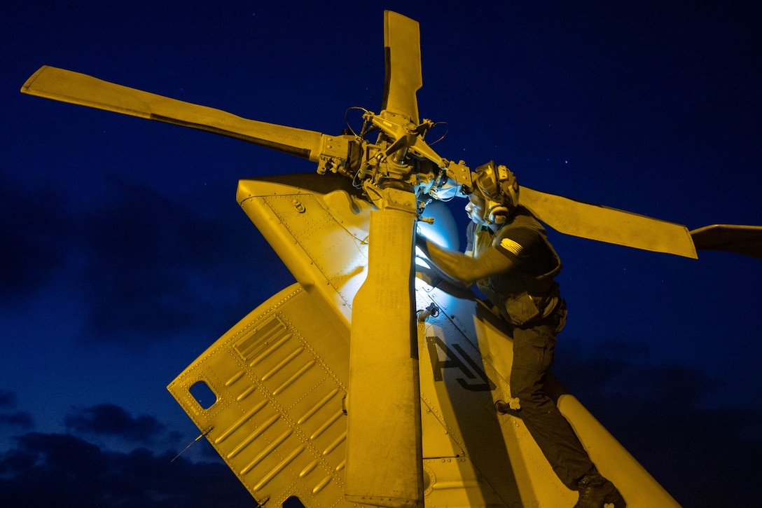A sailor conducts routine maintenance on the propeller of an MH-60S Sea Hawk.