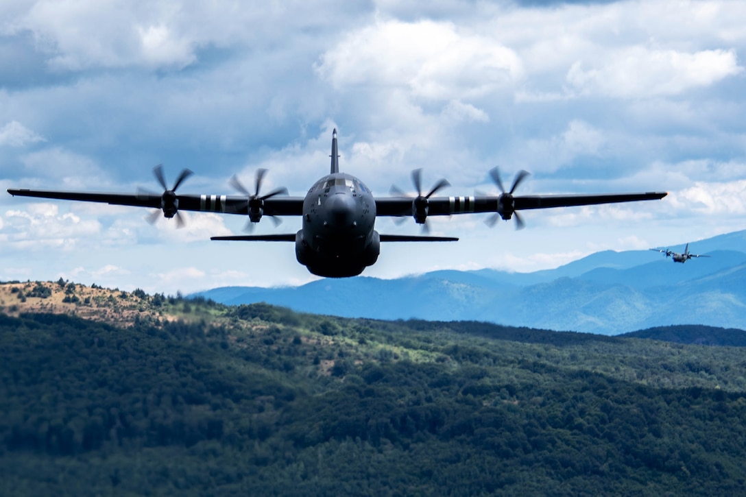 Planes fly low in formation over hilly ground.