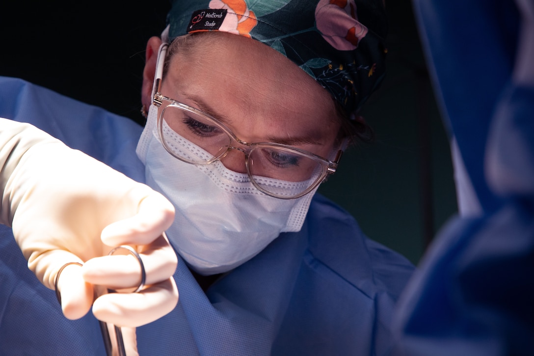 A surgeon wearing a mask looks down at her patient.
