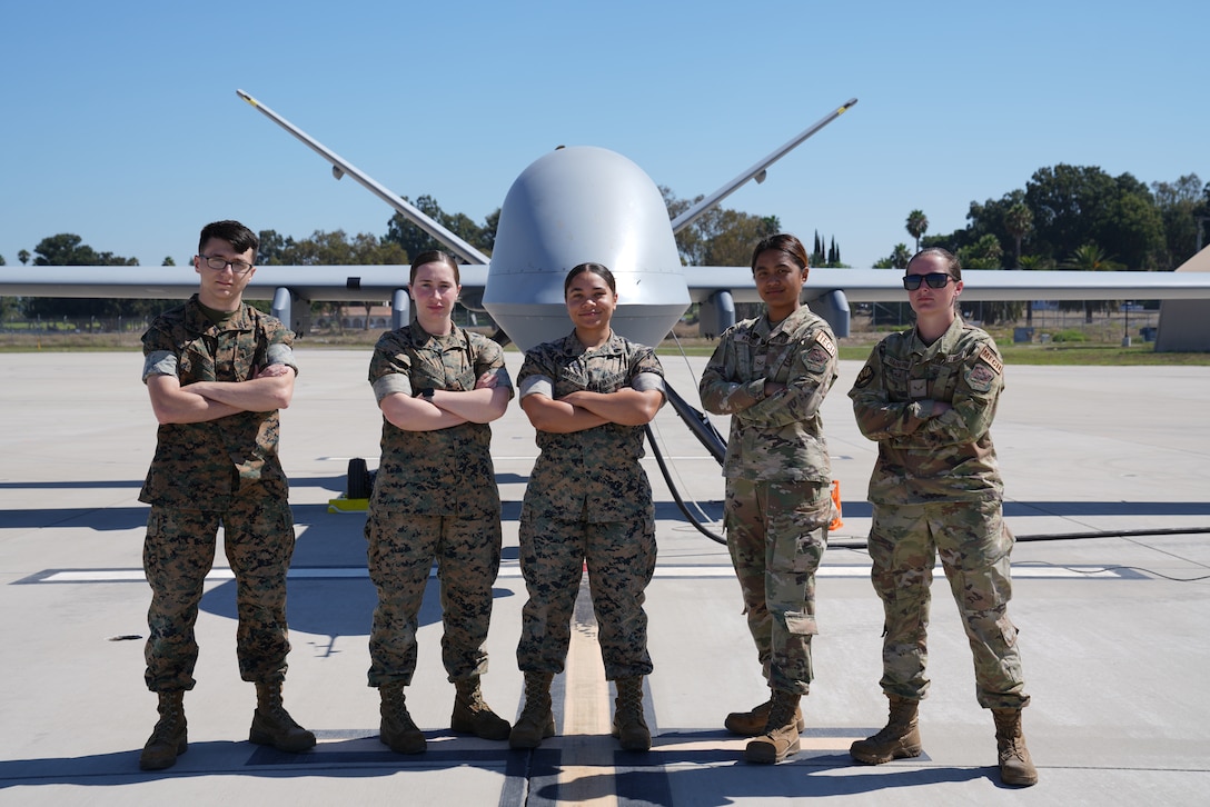 U.S. Marines, assigned to Marine Corps Base Camp Pendleton, and U.S. Air Force Airmen, assigned to the 432nd Wing/432nd Air Expeditionary Wing, pose in front of an MQ-9 Reaper at Marine Corps Base Camp Pendleton, California, August 23, 2023. The agile combat employment (ACE) exercise known as Agile Hunter saw an Air Force MQ-9 remotely piloted aircraft land on Camp Pendleton, a Marine Corps base, for the first time ever. (U.S. Air Force photo by Senior Airman O'Shea)