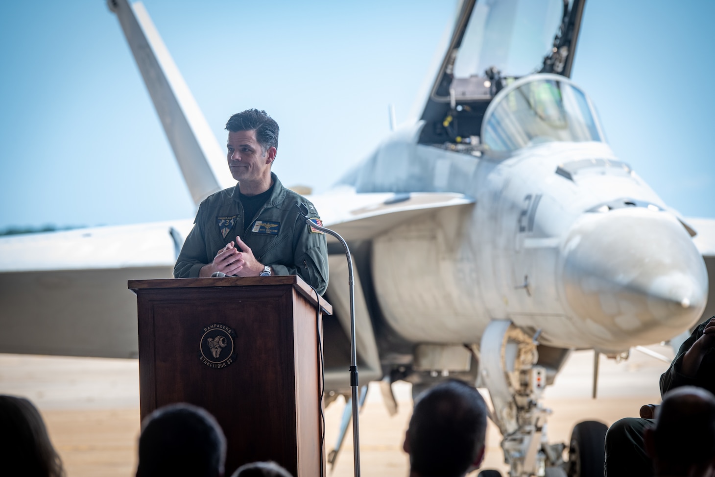 Pilot speaks at a podium in front of jets