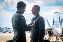 Pilot pins a medal to another pilot in front of jets