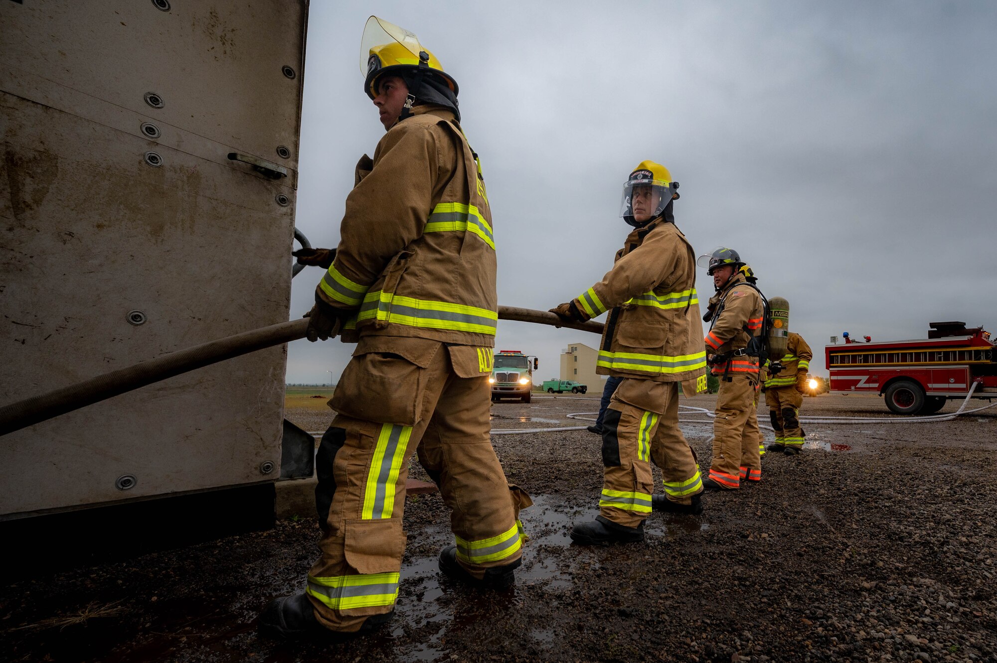 A group of 5th Civil Engineer Squadron fire protection specialists hold a fire house so it doesn't get caught on anything for the attack team during a live structure fire exercise Minot Air Force Base, North Dakota, Aug. 21, 2023. The usual working pressure of a firehose can vary between 116 and 290 psi. (U.S. Air Force photo by Airman 1st Class Alexander Nottingham)
