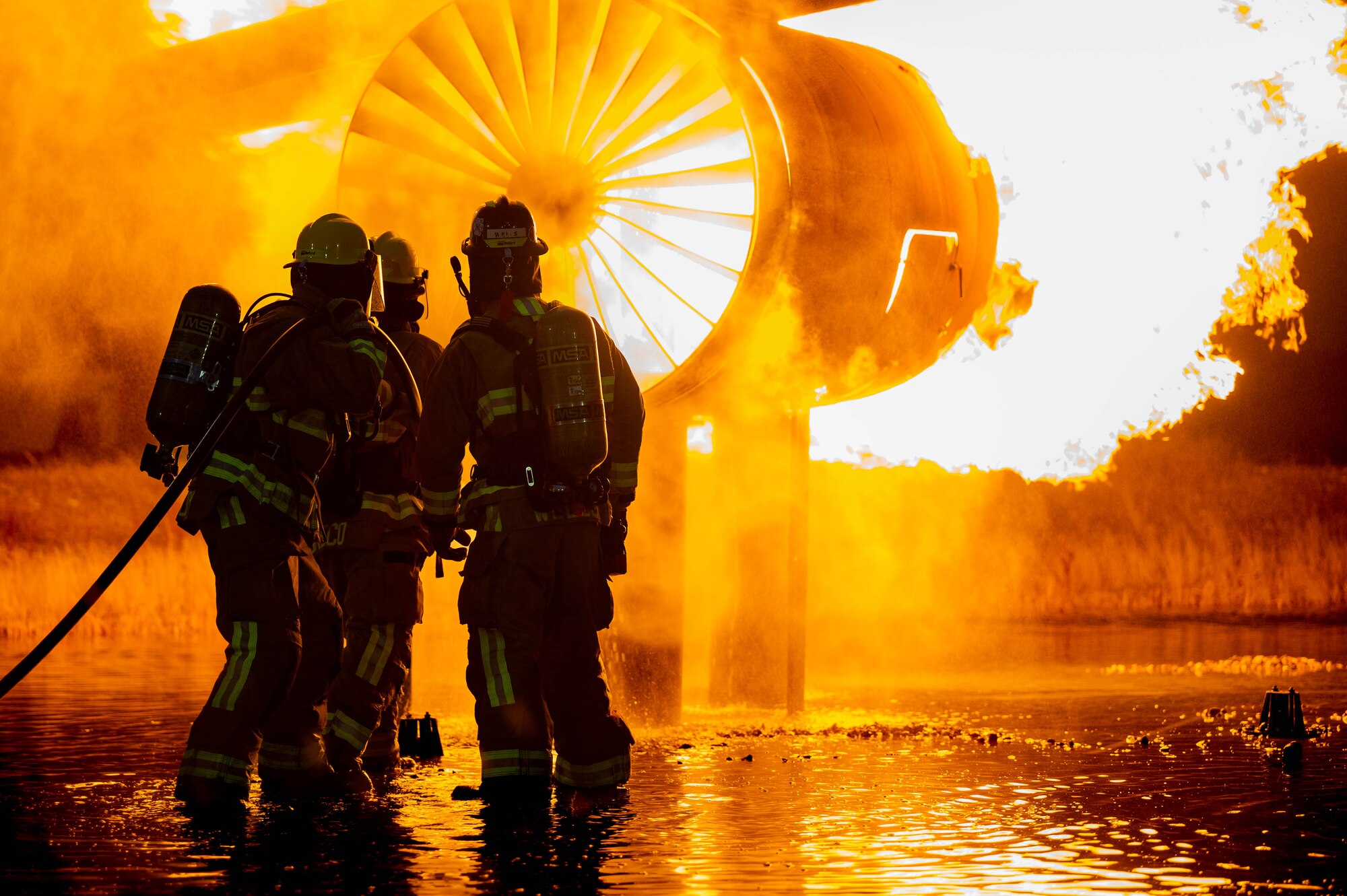 A group of 5th Civil Engineer Squadron fire protection specialists extinguish an ongoing fire during a live jet fire exercise at Minot Air Force Base, North Dakota, Aug. 21, 2023. These military firefighters protect people, property, and the environment from fires and disasters. (U.S. Air Force photo by Airman 1st Class Alexander Nottingham)