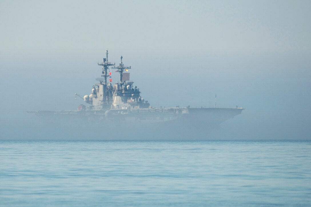 A ship sails in open water on a foggy day.