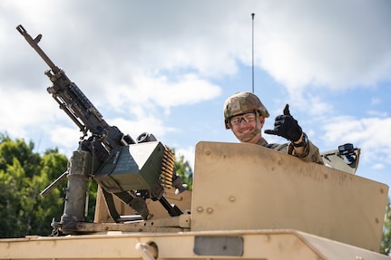 U.S. Army Pfc. Buckley Ryan, military police assigned to the 143rd Military Police Company, 192nd Military Police Battalion, Connecticut Army National Guard, poses for a photo from the turret of his High Mobility Multipurpose Wheeled Vehicle, or humvee, before vehicle gunnery at Fort Drum, New York, Aug. 13, 2023. Despite this being his first annual training period, and first time manning the M240L machine gun as a vehicle gunner, Ryan successfully engaged all targets and became the fifth gunner in his unit to qualify.