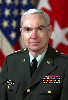 A man in a dress green uniform in front of a US flag