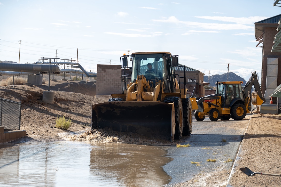 Public Works Division personnel with the Marine Corps Air-Ground Combat Center (MCAGCC), clear water out of a low point due to Tropical Storm Hilary at MCAGCC, Twentynine Palms, California, Aug. 21, 2023. MCAGCC is committed to ensuring effective and efficient recovery actions following extreme weather. (U.S. Marine Corps photo by Lance Cpl. Anna Higman)