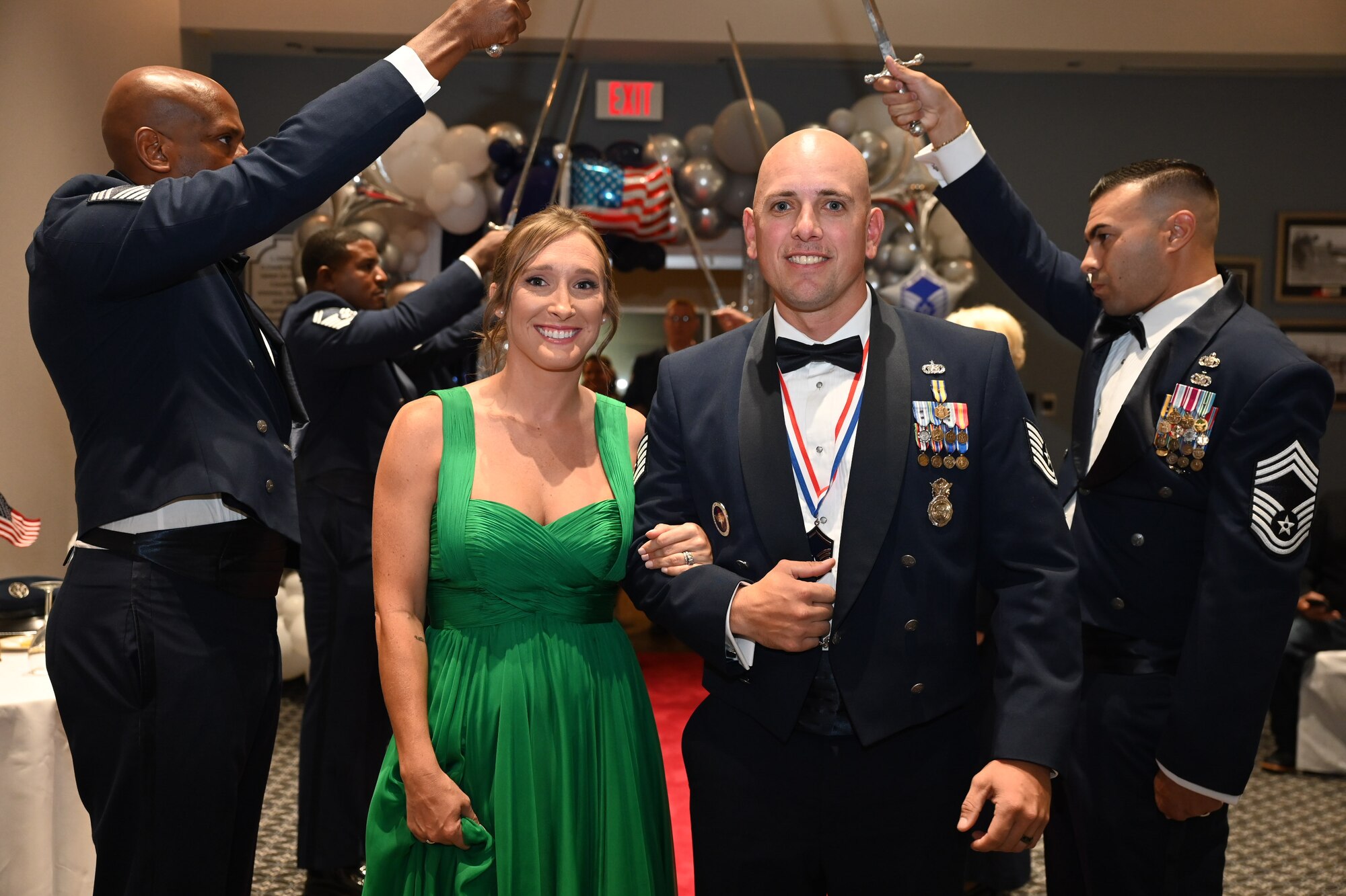 U.S. Air Force Master Sgt. Select Drew Eaton, 17th Security Forces Squadron logistics overhead, and his spouse, Malorie Eaton, walk through the saber cordon, inducting him into the highest tier of the enlisted force during the Senior Noncommissioned Officer Induction Ceremony at the Powell Event Center, Goodfellow Air Force Base, Texas, Aug. 18, 2023. Each inductee entered the room through a saber cordon, which is used to salute the new SNCOs to show respect for the sacrifice and commitment the inductees have taken to earn the rank of master sergeant. (U.S. Air Force photo by Airman 1st Class Evelyn D’Errico)